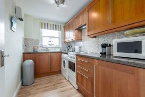 a kitchen with wooden cabinets and a microwave at Marine Park No 10 - Elie in Elie +10 photos