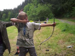a young boy holding abow in a field at Schullandheim Kronenburg GmbH in Kronenburg +1 photo