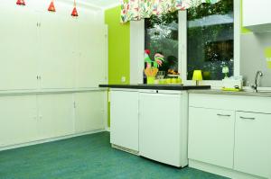 a kitchen with white cabinets and a window at Schullandheim Kronenburg GmbH in Kronenburg