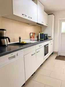 Una cocina con gabinetes blancos y una encimera negra. en Turmhof Jüterbog, en Jüterbog