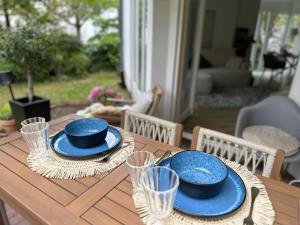 a wooden table with blue plates and glasses on it at Ruhige Stadtperle mit Garten in Wiesbaden
