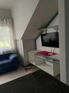 een woonkamer met een blauwe bank en een televisie bij Villa Rainer in Porto Seguro