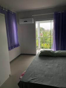 een slaapkamer met een bed met paarse gordijnen en een balkon bij Villa Rainer in Porto Seguro