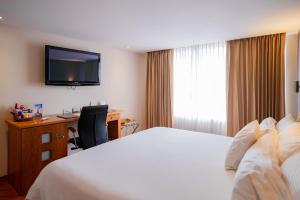 昆卡埃多拉多酒店的配有床、书桌和电视的酒店房间
