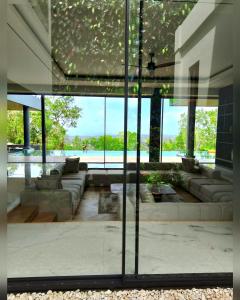 a living room with couches and a large glass wall at House Of Sea Breeze in Uluwatu