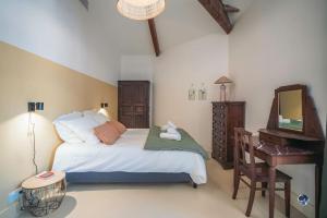 une chambre avec un lit, un bureau et une télévision dans l'établissement Mas Evalla, Charme, Piscine Chauffée et Vue Unique, à Saint-Pons-la-Calm 42 autres photos