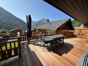 a wooden deck with a table and chairs on it at Nouveau ! Chalet pied des pistes in Champagny-en-Vanoise
