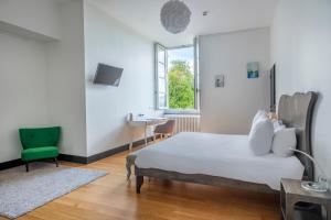 a bedroom with a bed and a green chair at Château de Briançon, The Originals Relais in Bauné