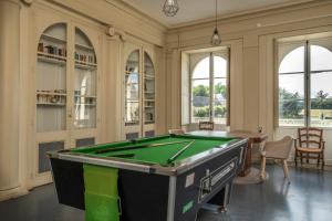 a pool table in a room with windows at Château de Briançon, The Originals Relais in Bauné