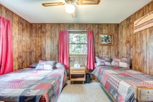 two beds in a room with wooden walls and red curtains at Cabin in Boulder Junction with Fire Pit and Deck! in Boulder Junction