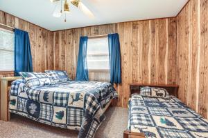 two beds in a room with wood paneling at Cabin in Boulder Junction with Fire Pit and Deck! in Boulder Junction