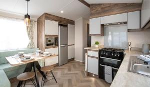 una cocina con una mesa y una estufa horno superior en FRESHWATER BEACH HOLIDAY HOME, en Burton Bradstock