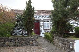 a white house with a red door and a stone wall at casa da Madrinha in Nordeste +6 photos