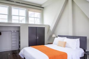 une chambre avec un grand lit avec une couverture orange dans l'établissement Downtown Luxury 1BR Loft, à Milwaukee