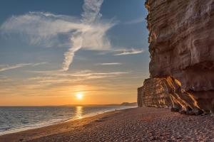 una puesta de sol en una playa cerca del océano en FRESHWATER BEACH HOLIDAY HOME, en Burton Bradstock