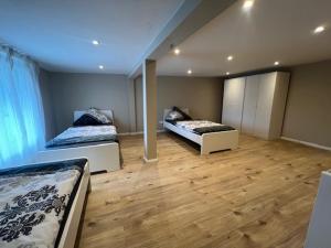 two beds in a large room with wooden floors at Serena Monteur Apartment in Rodenbach