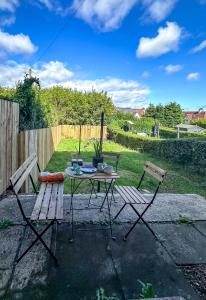 a picnic table and two chairs in a backyard at Colourful life-house near Glasgow in Clydebank