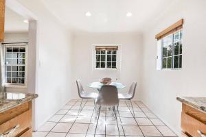 a kitchen with a table and chairs and two windows at Updated 3-Bedroom LA Home with Backyard, BBQ & Family-Friendly Amenities in Los Angeles