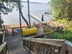 een houten vlonder die naar een strand met een aanlegsteiger leidt bij Family Shoreline Hideaway in Ortonville