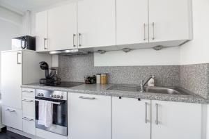 a white kitchen with white cabinets and a sink at Sweet-Neipperg in Luxembourg +1 photo