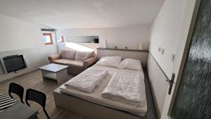 a small bedroom with a bed and a couch at Apartmán Stratos in Ostružná