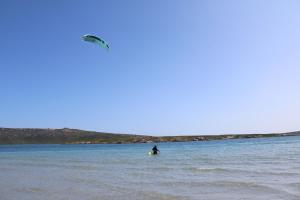 a person standing in the water with a kite at Downwind - Visit Langebaan in Langebaan