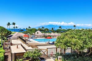 a resort pool with tables and umbrellas and palm trees at Maui Eldorado Condo F203 in Kaanapali