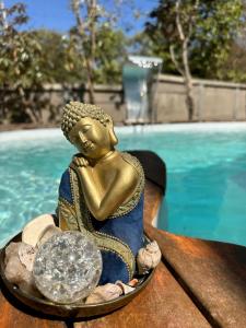 a statue of a buddha sitting next to a pool at Woodhouse Tranquilidade e Conforto no Paraíso, piscina aquecida e ar condicionado in Alto Paraíso de Goiás