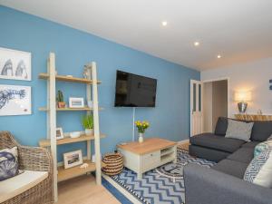 Una sala de estar con un sofá y un televisor. en Coastal Haven, en Bude