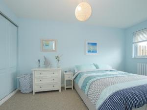 Dormitorio azul con cama y mesita de noche en Coastal Haven, en Bude