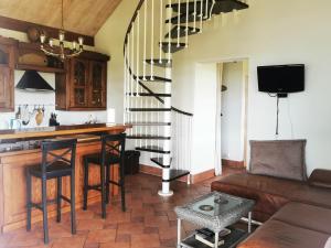 a living room with a kitchen and a spiral staircase at Svenceles 25 sodyba Namas su pirtimi ir krantine in Svenele