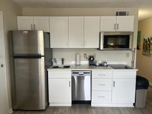Una cocina con gabinetes blancos y un refrigerador de acero inoxidable. en Summer Sands - 104 by Sea Scape Properties, en Wrightsville Beach