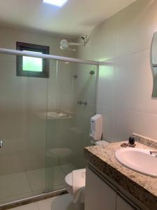a bathroom with a glass shower and a sink at Villas Supreme Apartamentos in Maceió