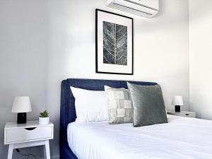 1 dormitorio con cama blanca y cabecero azul en Family Home at Boronia, en Boronia