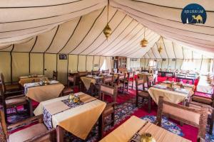 a restaurant with tables and chairs in a tent at Sahara Zen Luxury Camp in Merzouga