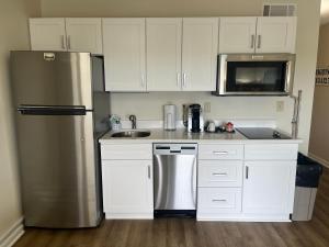 Una cocina con gabinetes blancos y un refrigerador de acero inoxidable. en Summer Sands - 202 by Sea Scape Properties, en Wrightsville Beach