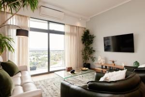 a living room with a white couch and a large window at When Away - Your Home Away from Home in Pretoria