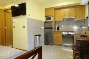 Una cocina con electrodomésticos de acero inoxidable y gabinetes de madera. en Apartamentos Ababides Playa, en Baiona