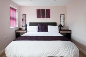 a bedroom with a large bed with two night stands at QF Living Apartments in Caister-on-Sea