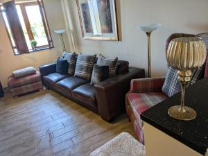 a living room with a leather couch and a chair at Cozy Cottage Close to Haworth Sleeps 2 with Garden in Keighley