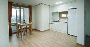 a kitchen with a table and chairs and a refrigerator at Bowhill Resort & Pension in Seogwipo
