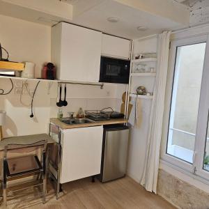 una pequeña cocina con armarios blancos y una ventana en Studette Rémilly à Versailles, en Versalles 11 fotos más