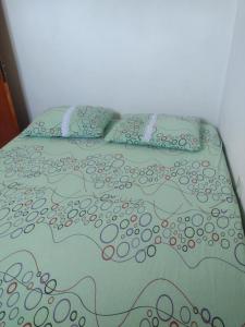 a bed with a colorful comforter and pillows at Apartamento avenida 07 com ar condicionado in São Thomé das Letras
