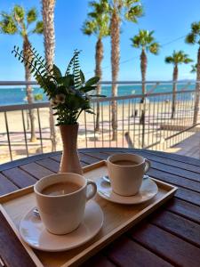 two cups of coffee on a tray with a vase with a plant at Blue Home in Los Alcázares