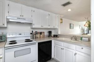 a kitchen with white cabinets and a white stove top oven at Pier Point 17 in St. Augustine