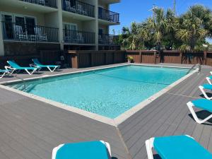 a swimming pool with lounge chairs and a building at Summer Sands - 304 by Sea Scape Properties in Wrightsville Beach