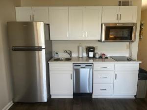a kitchen with white cabinets and a stainless steel refrigerator at Summer Sands - 304 by Sea Scape Properties in Wrightsville Beach