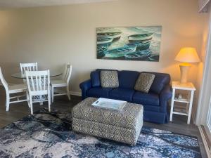 a living room with a blue couch and a table at Summer Sands - 304 by Sea Scape Properties in Wrightsville Beach