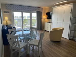 a living room with a table and chairs and a kitchen at Summer Sands - 302 by Sea Scape Properties in Wrightsville Beach