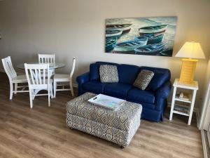 a living room with a blue couch and a table at Summer Sands - 302 by Sea Scape Properties in Wrightsville Beach